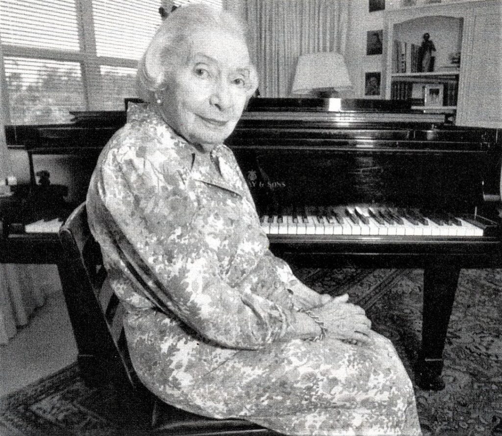 Woman wearing patterned dress in front of piano