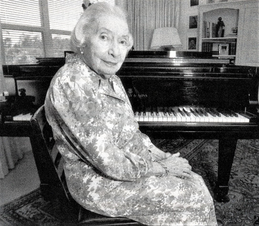 Woman wearing patterned dress in front of piano