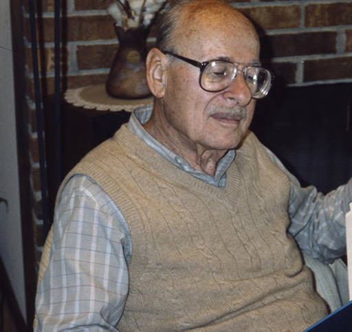 Man looking down wearing sweater vest and patterned shirt