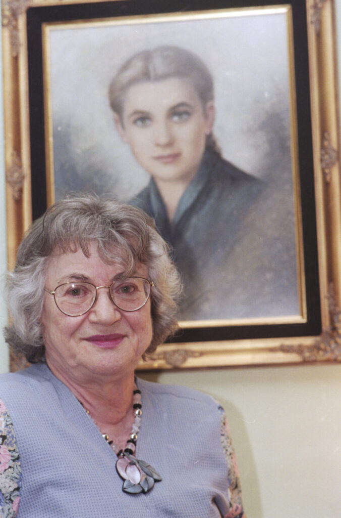 Dora Nesselroth standing next to photo of herself younger