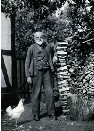 man standing outside next to firewood and chicken