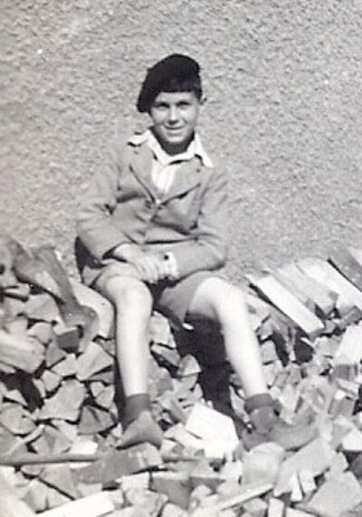 Max Herzel sitting on ruins outside smiling wearing hat