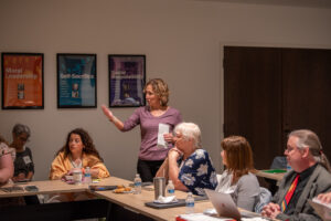 Amy Mcdonald in a purple shirt stands in the center of the photo talking to a group of teachers. 